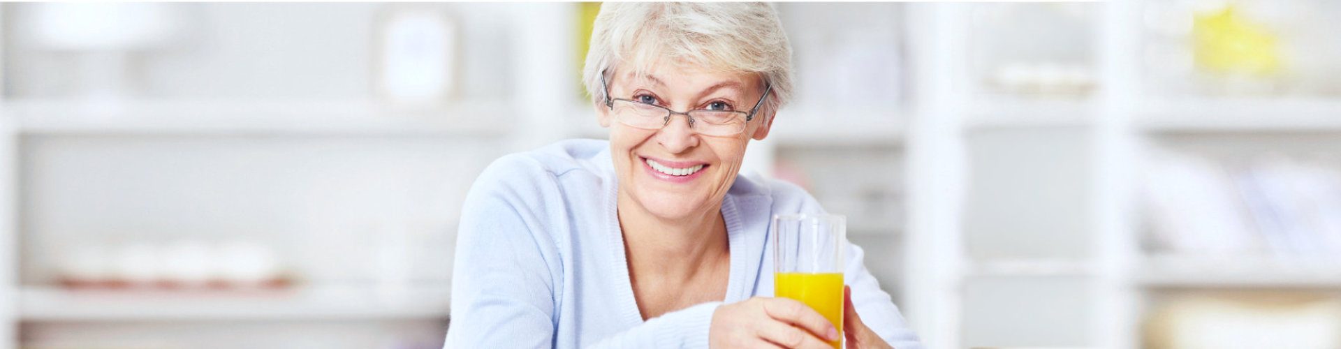 senior woman smiling holding a glass of juice