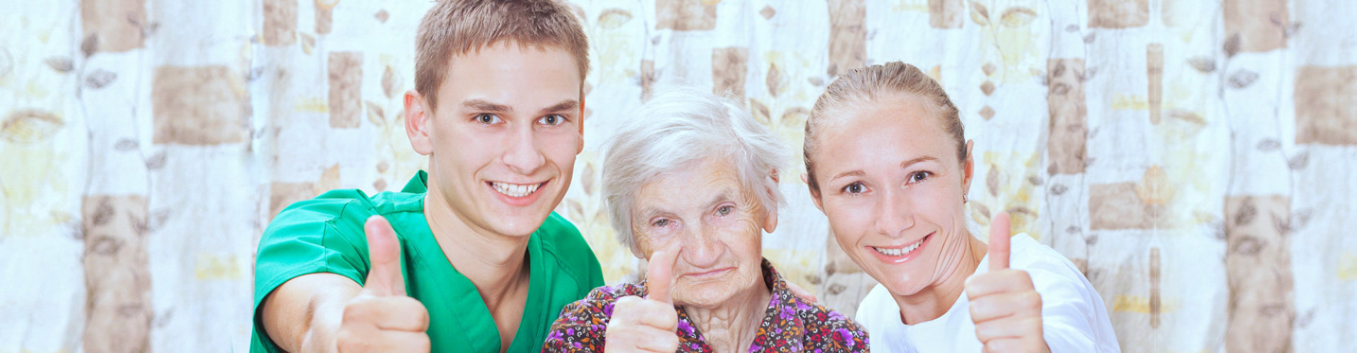 caregivers and elder woman showing thumbs up